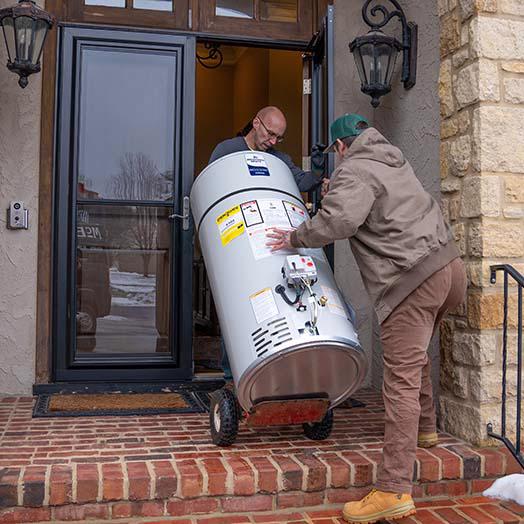 McElroy's plumbing technicians bring a new water heater into a home.