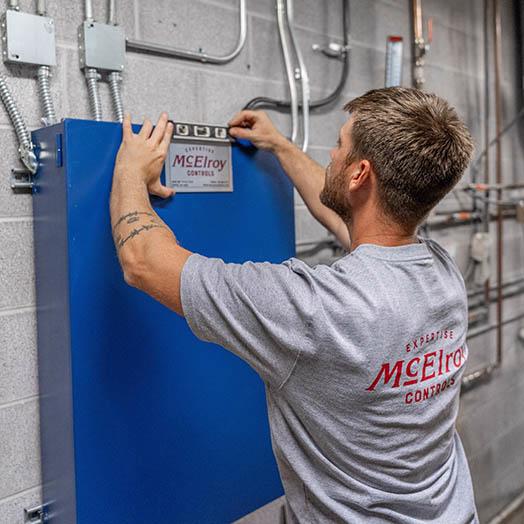 Dylan Hunninghake attaches a McElroy Controls nameplate to a new controls cabinet.