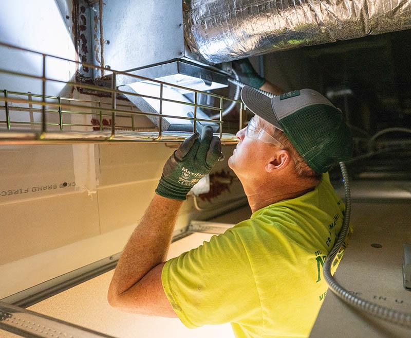 McElroy's Tech inspecting damper with flashlight.