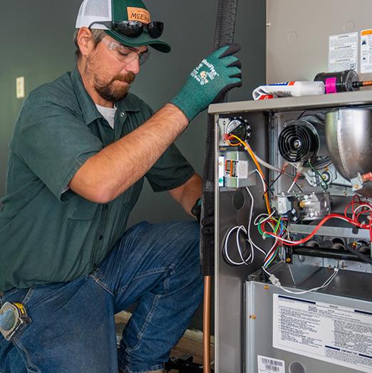 Ben Walker adds insulation to the refrigerant line of a new heating and air system he’s helping to install in an outbuilding that is being transformed into a year-round workout area.