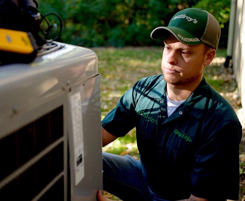 McElroy's residential HVAC technician performs maintenance on an air conditioner condensing unit