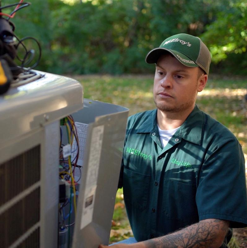 McElroy's residential HVAC technician performs scheduled maintenance on an outdoor air-conditioning condenser unit.