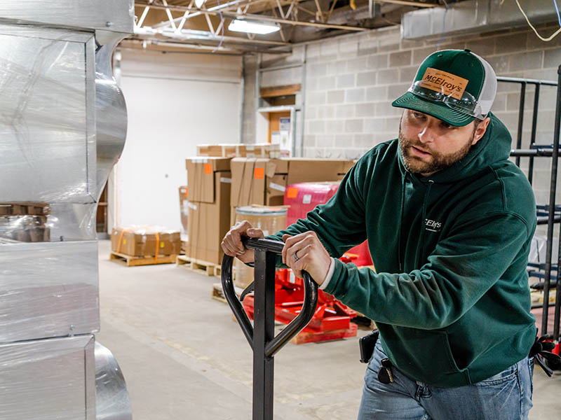 Rhett Renolds uses a pallet jack to move materials in the McElroy’s construction plumbing warehouse and prefabrication facility.