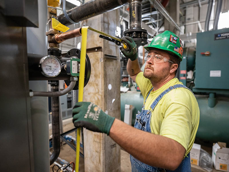 Nate Zirkle, McElroy’s construction division plumber/pipefitter, takes measurements for a line of copper pipe.