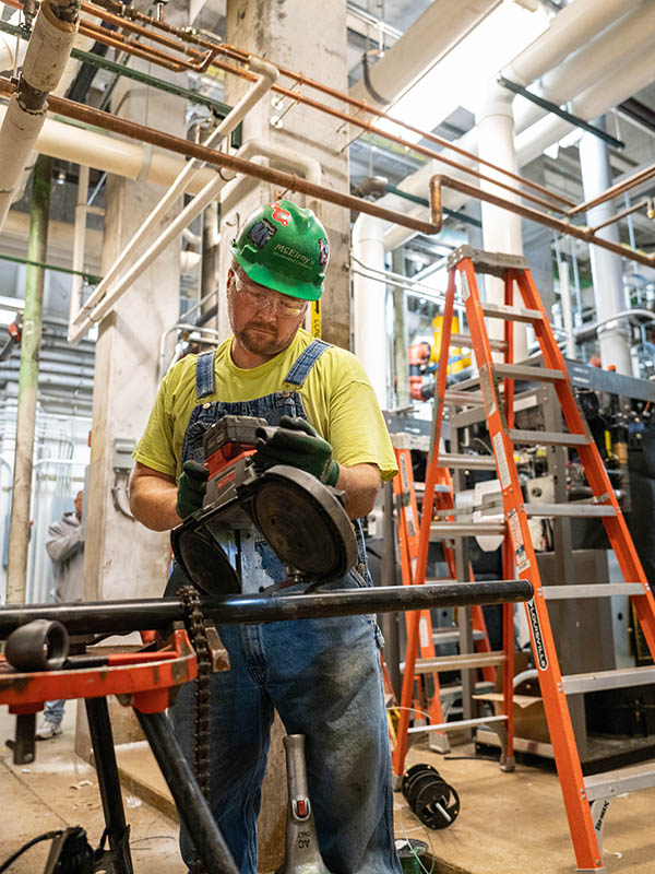 Nate Zirkle, McElroy’s construction division plumber/pipefitter, cuts pipe for an HVAC renovation project.