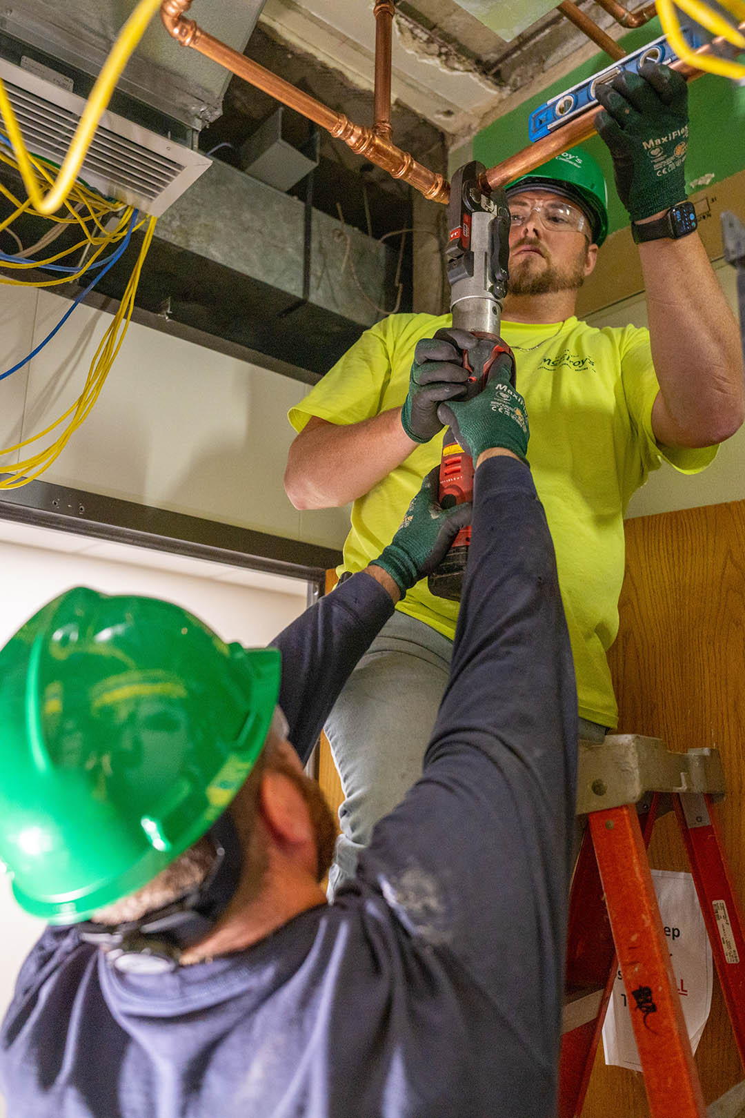 Clint Mayer and Dayne Shelman, both of McElroy’s, work together while installing crimped copper pipe.