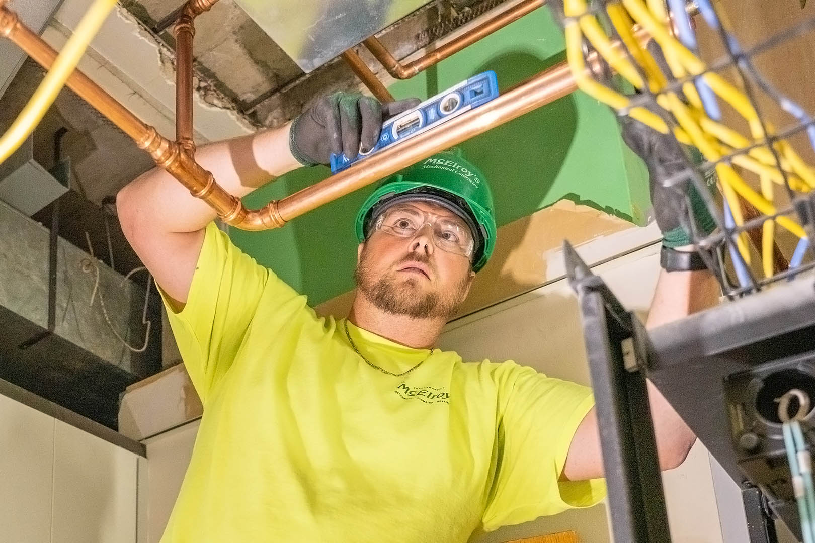 McElroy’s commercial construction foreman, Clint Mayer, checks the level of a new pipe he’s installing.