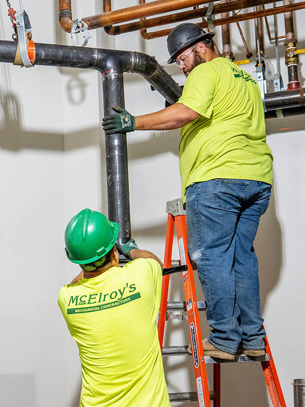McElroy’s plumber/pipefitters, Dusty Bergquist and Chris Perkins (on ladder), work together constructing a mechanical room.