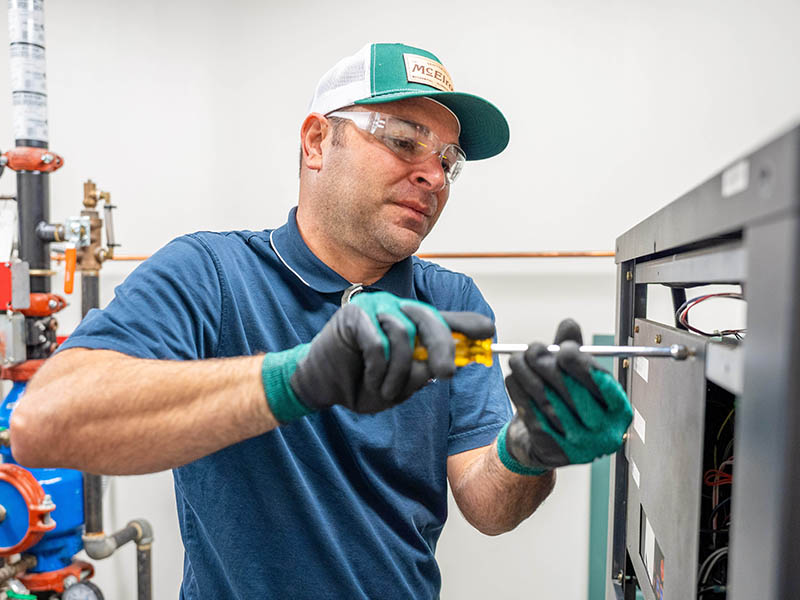 Phil Harper, McElroy’s commercial project supervisor, works on the electronics of a boiler at a Topeka health clinic.