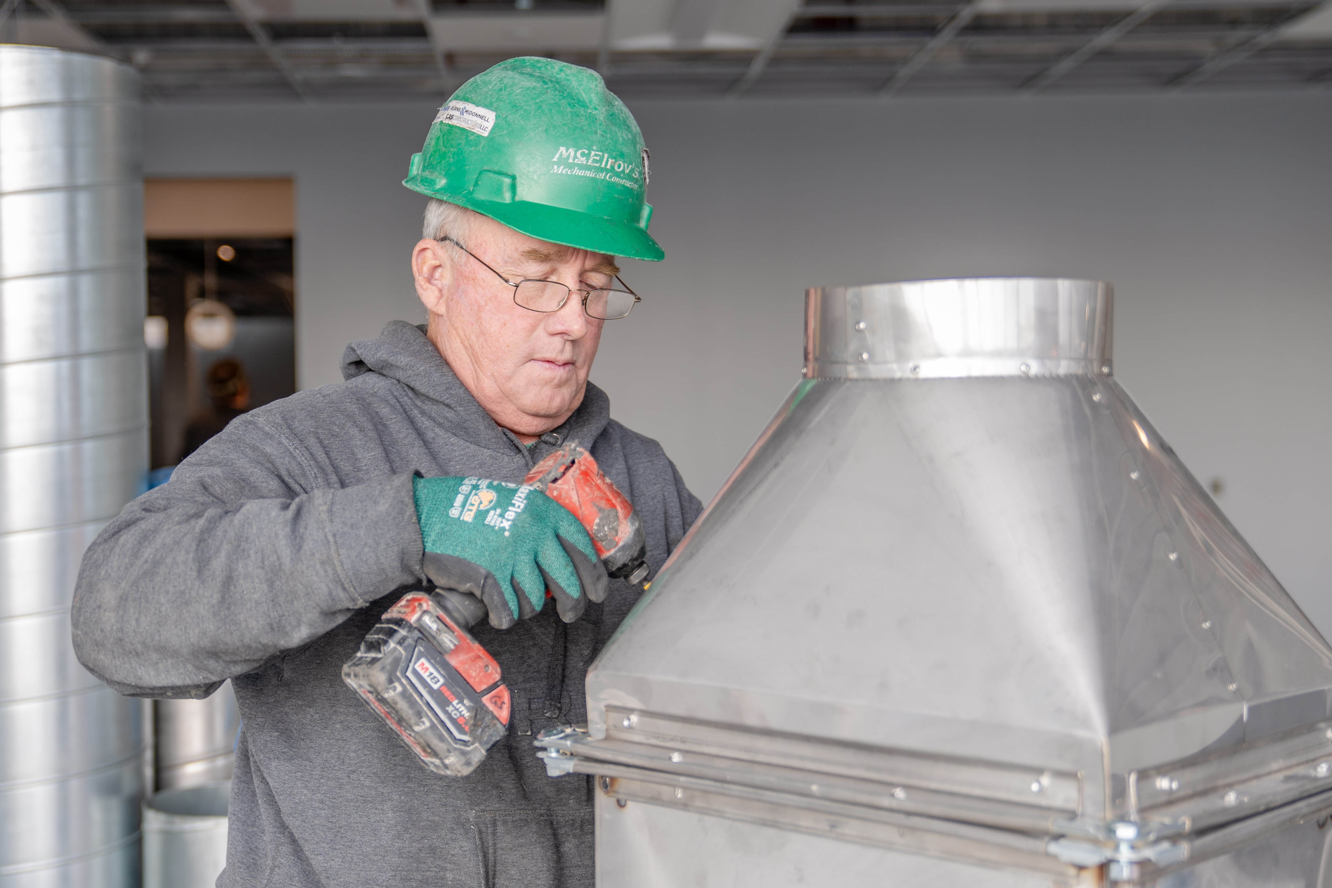 Gail Sage, McElroy’s commercial construction sheet-metal foreman, fastens a reducer onto a large, rectangular air duct.