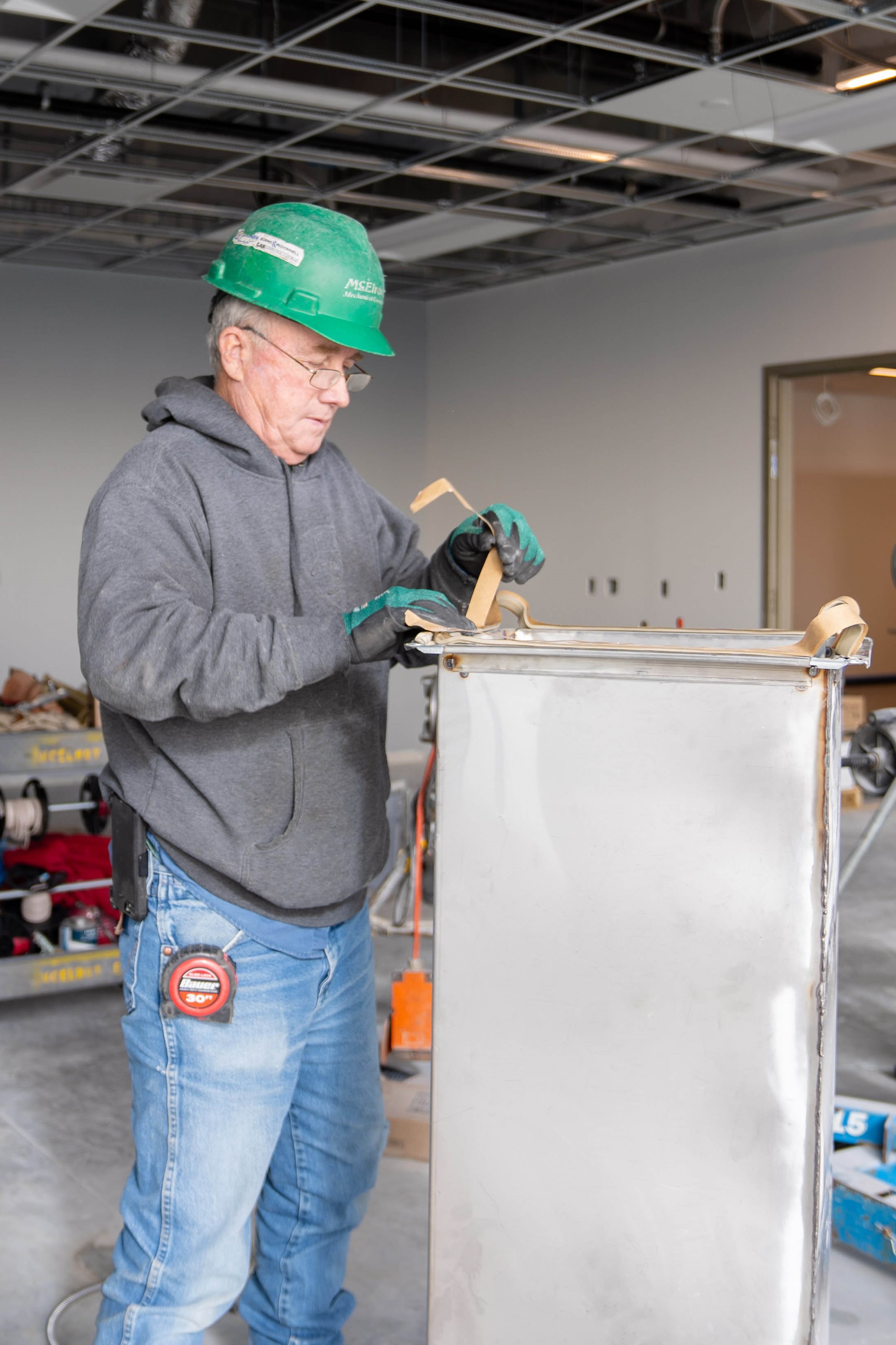 Gail Sage, McElroy’s commercial construction sheet-metal foreman, applies duct gasket tape to a large section of rectangular duct.