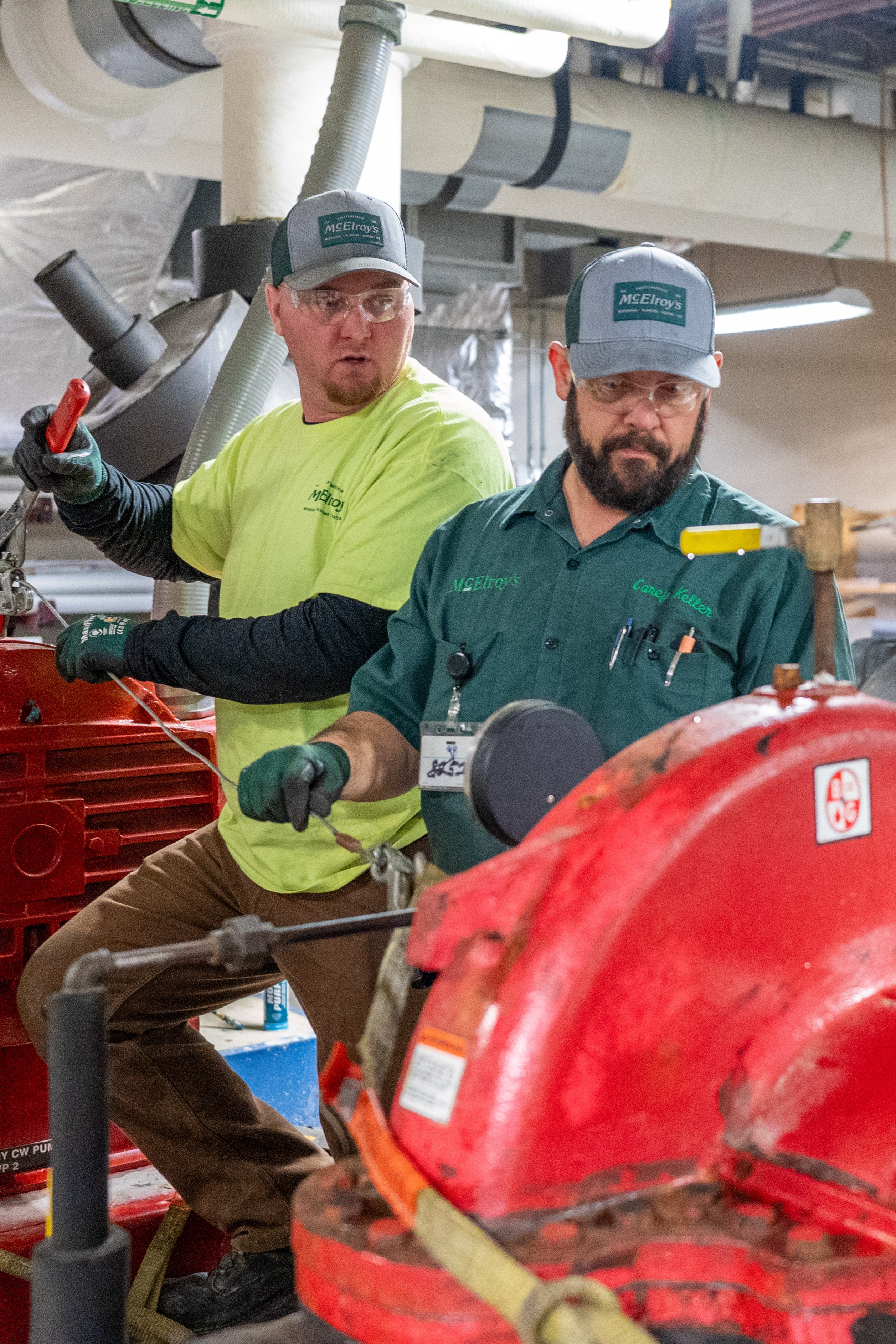 Corey Keller and Chriss Reece, McElroy’s commercial HVAC service technicians, perform maintenance on an HVAC system pump.
