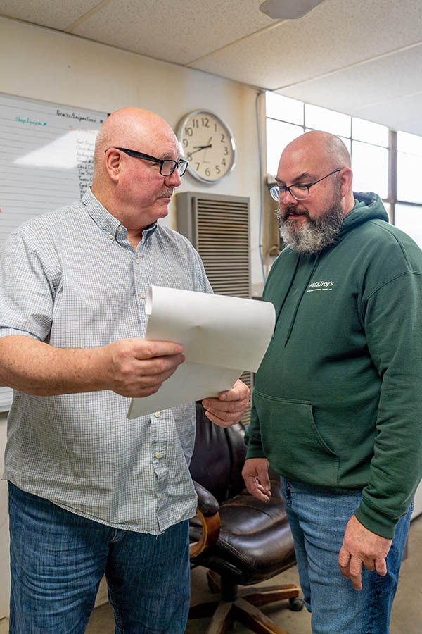 Martin Decker, Jr., McElroy’s sheet metal manager, discusses a project with Anthony Decker, sheet metal shop foreman.