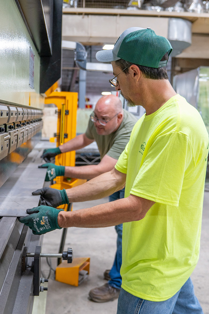David Dechand and Anthony Decker, both of McElroy’s, use a sheet-metal brake to bend a metal plate.