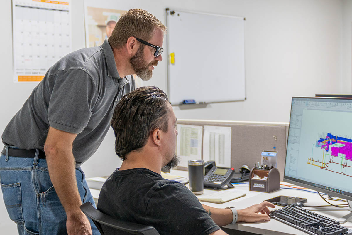 Scott Schneider, McElroy’s commercial project supervisor, reviews plans with Aaron Thompson, McElroy’s VDC/fabrication shop supervisor.