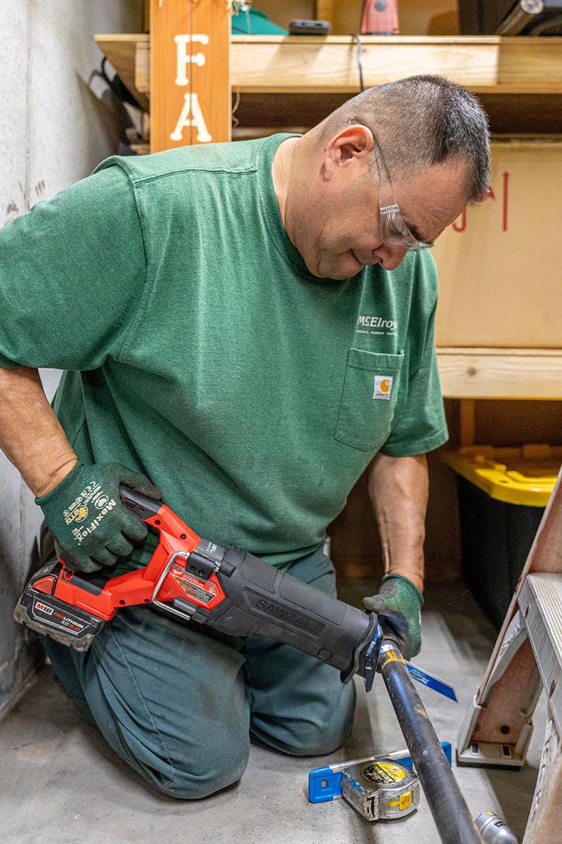 Junior Barajas, McElroy’s plumber, cuts steel pipe to length during installation of a new gas line.