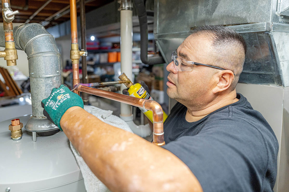 Junior Barajas, McElroy’s plumber, brazes copper piping as he installs a new water heater.