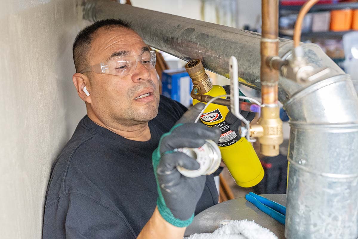 Junior Barajas, McElroy’s plumber, connects a gas shutoff valve for a water heater.