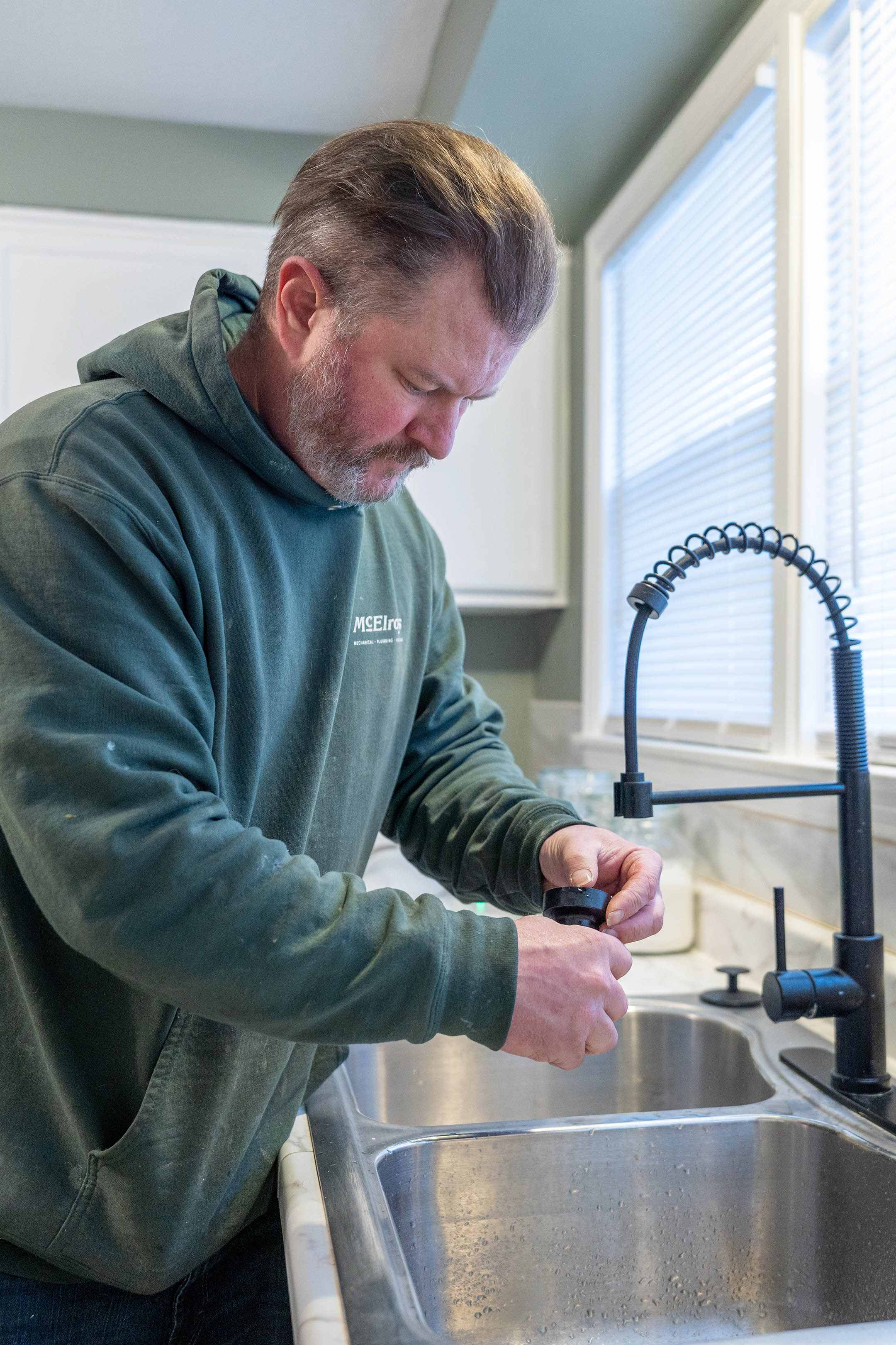 McElroy’s plumber James King cleans and repairs a homeowner’s kitchen faucet.